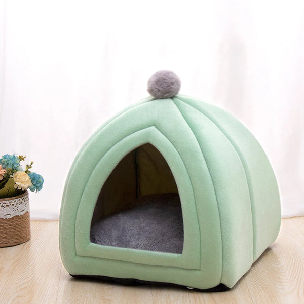 A light green, dome-shaped cat bed with a gray fluffy top and an arched entrance.