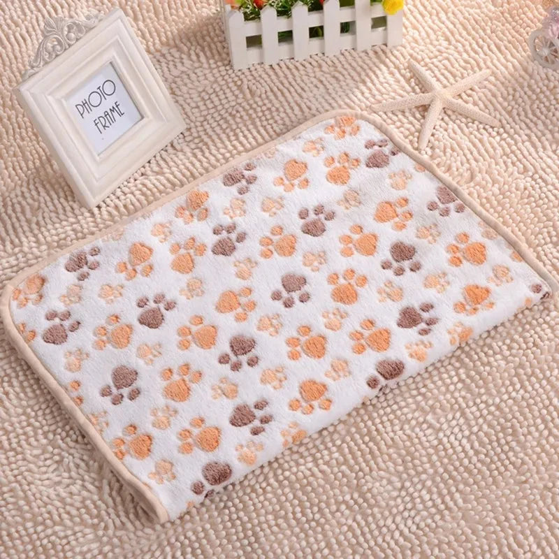 A beige fleece pet bed mat cover with a paw print pattern is displayed on a textured fabric next to a photo frame.