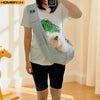 A person wearing a white t-shirt and dark shorts is holding an adjustable crossbody dog sling carrier with a fluffy white dog