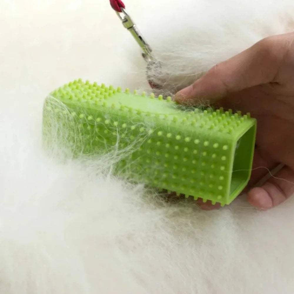 Eine Hand hält eine leuchtend grüne Silikonbürste zum Entfernen von Tierhaaren, mit Spänen von Haaren um sie herum.
