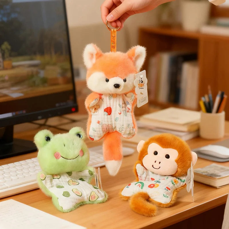 A hand is holding an orange fox plush toy and a green monkey plush toy on a wooden desk.
