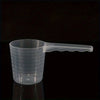 A transparent pet measuring spoon with a scale for dog and cat food, shown against a dark background.