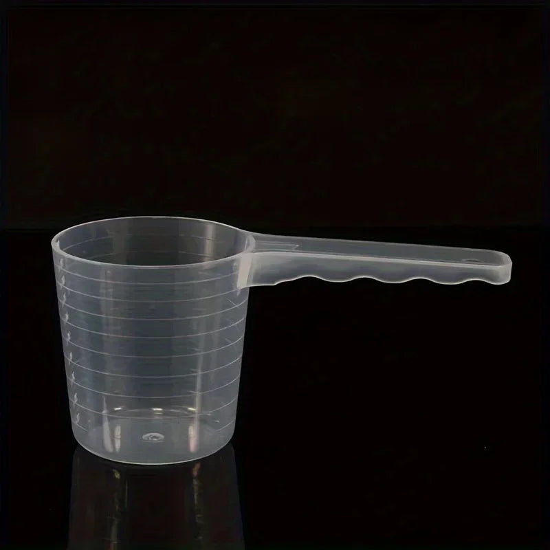 A transparent pet measuring spoon with a scale for dog and cat food, shown against a dark background.