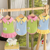 A cute cartoon dog dress in pink and green fabric hanging on a wooden rack.