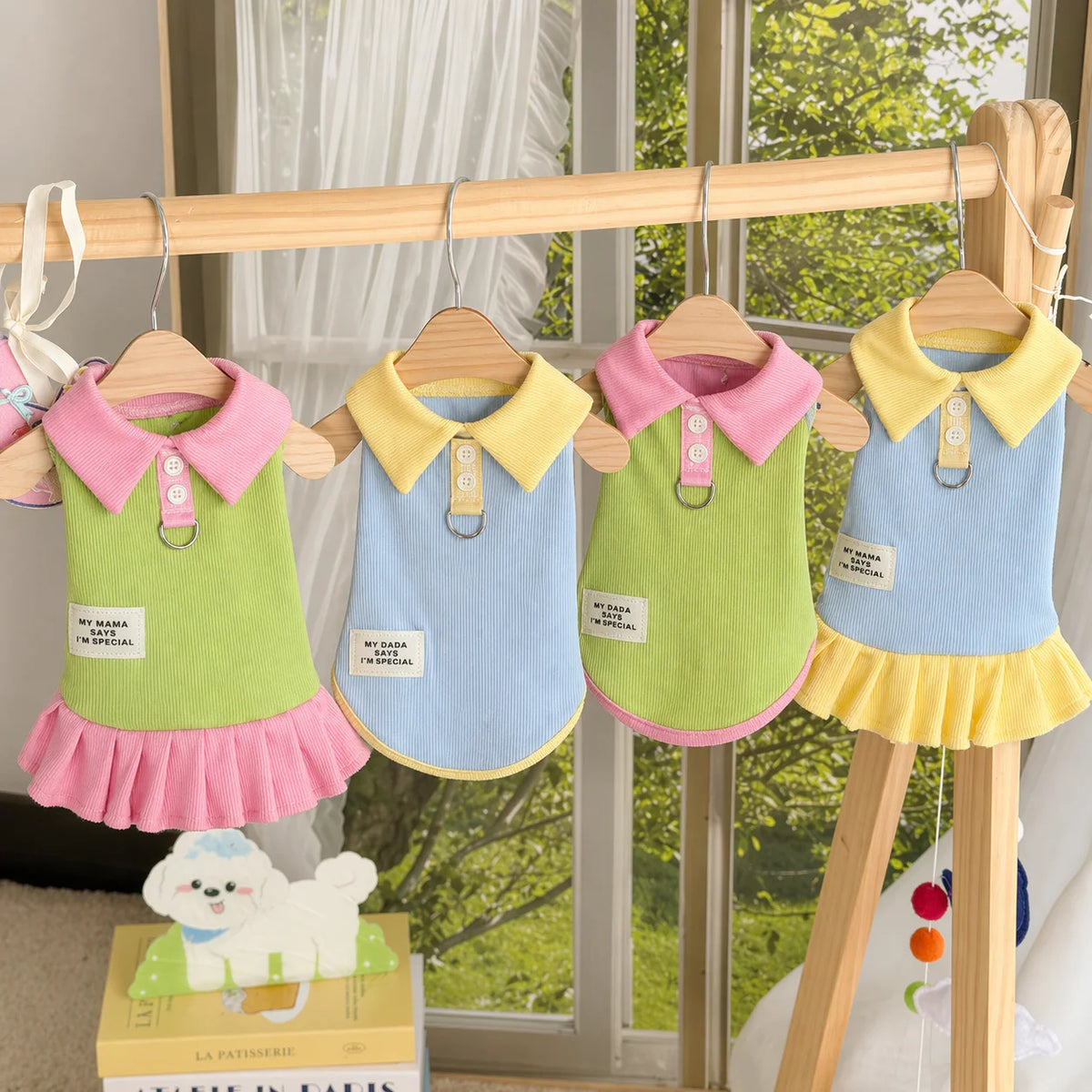 A cute cartoon dog dress in pink and green fabric hanging on a wooden rack.