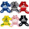 Eine Sammlung von vier Adidas Hundanzügen oder Mänteln in Blau, Grau, Rot und Gelb.