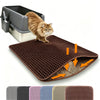 Eine braune Katzenstreumatte, auf der eine Katze sich putzt, neben einer Katzentoilette.