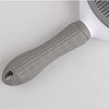 A close-up view of a gray pet hair removal brush with massage pins on a white background.