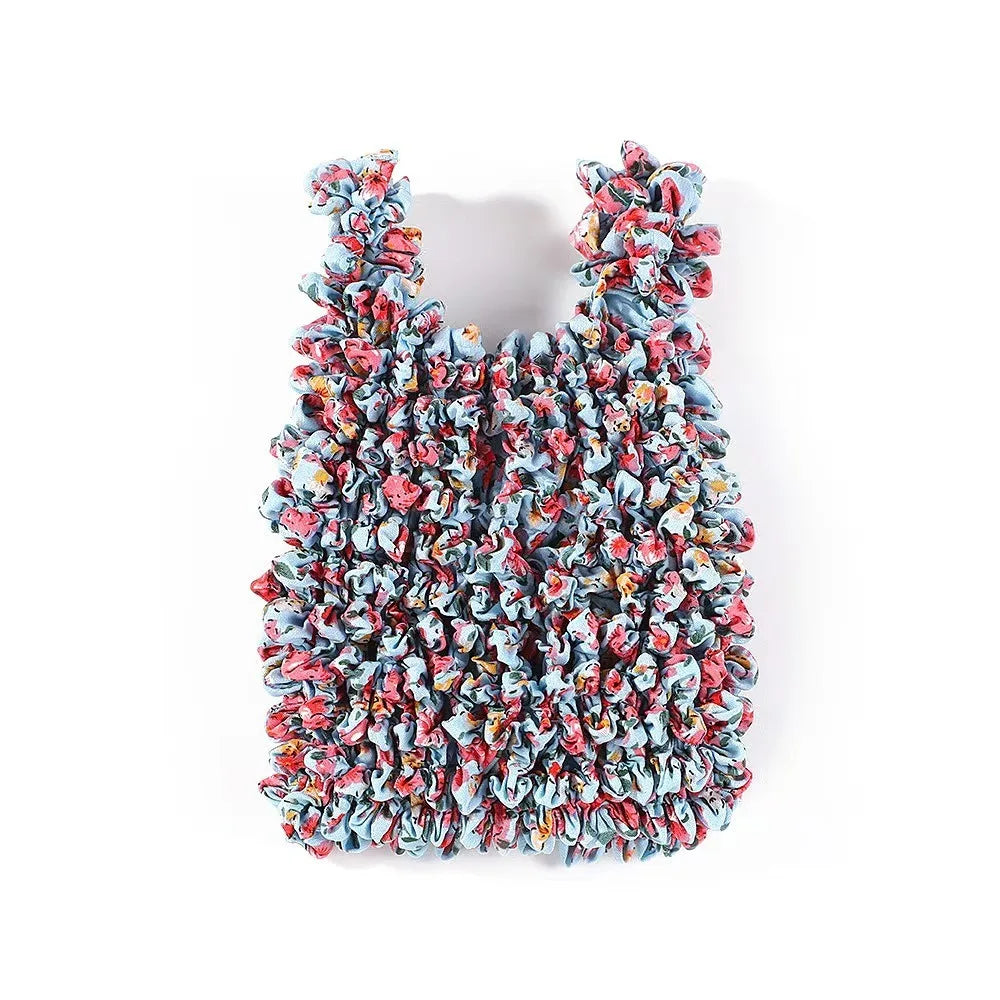 A close-up of a reusable foldable bubble shopping bag made of crinkled fabric in shades of blue and red.