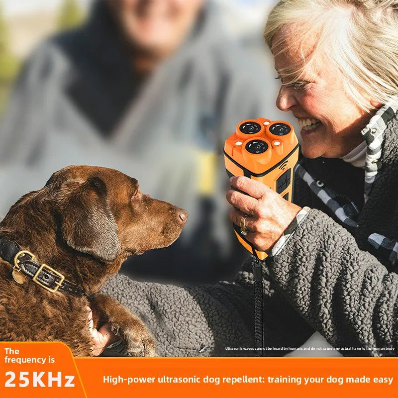 An elderly woman is using an orange ultrasonic dog repellent device while interacting with a brown dog.