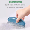 A hand is using a blue pet hair remover brush to gently sweep pet hair off a surface.