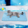 A gray cat lying on a blue cooling pet mat in front of a tiled background with ice effects.