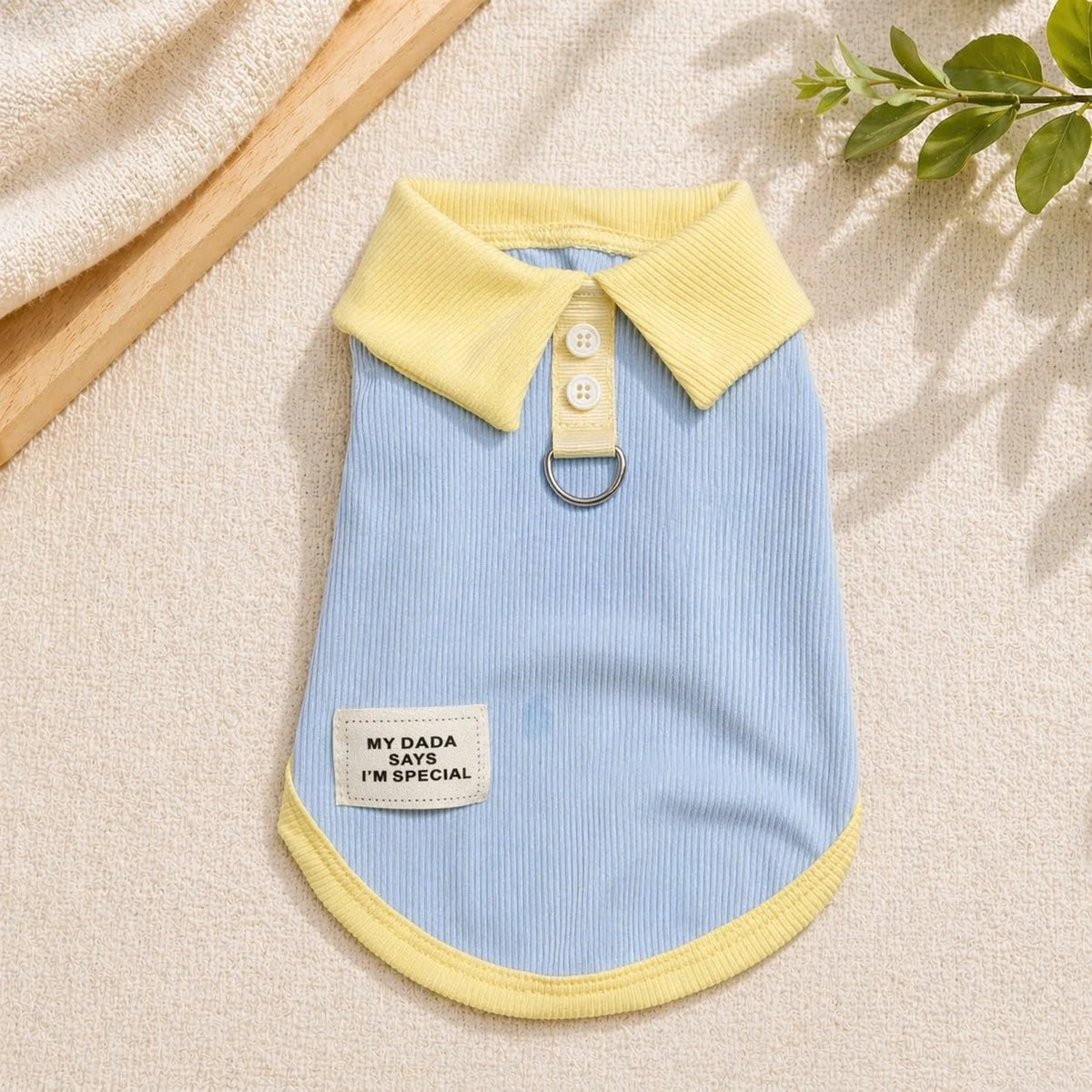 A light blue knitted dog dress with a yellow collar and a tag that says My Dada says I'm special