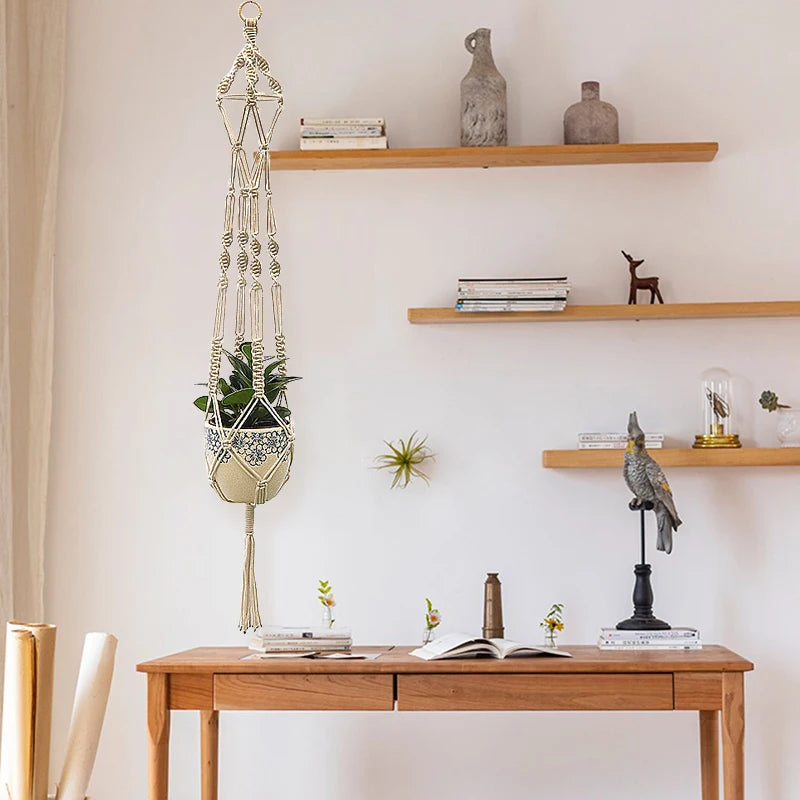 A macrame plant hanger displayed on a wall with various decorative items and books on wooden shelves.