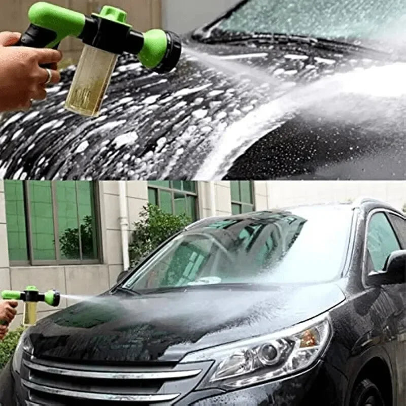 A hand sprays soapy foam onto a black car's windshield and body with a high-pressure cleaning gun.