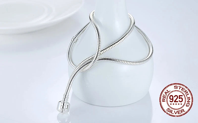 A silver snake chain necklace with a heart charm displayed on a white mannequin.