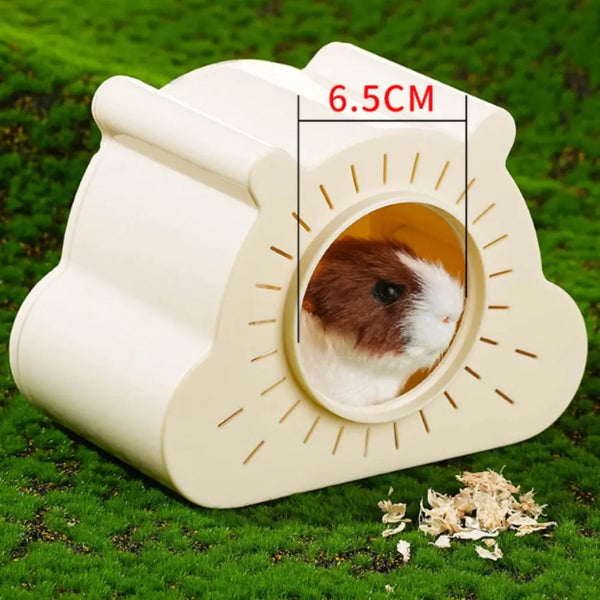 A beige cartoon hamster hideout house with a viewing window is placed on green grass.