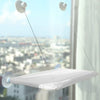 A white hanging cat hammock window perch suspended by thin lines and suction cups, viewed from below.