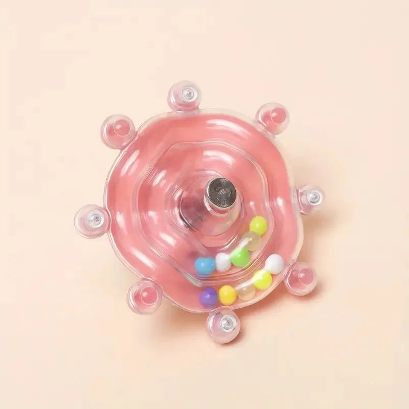 Pinkes, rotierendes Papagei-Spielzeug und Leckerliverteiler mit bunten Süßigkeiten drinnen.