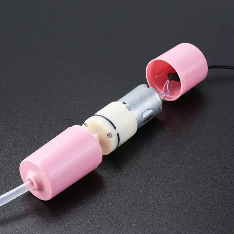 A pink and silver portable USB aquarium air pump with a clear tube and a pink nozzle.