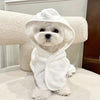A white fluffy dog wearing an absorbent quick-dry bathrobe, sitting on a white surface.