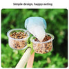 A blue bird is feeding from a clear cup attached to a clip-on feeder with a mounting bracket.
