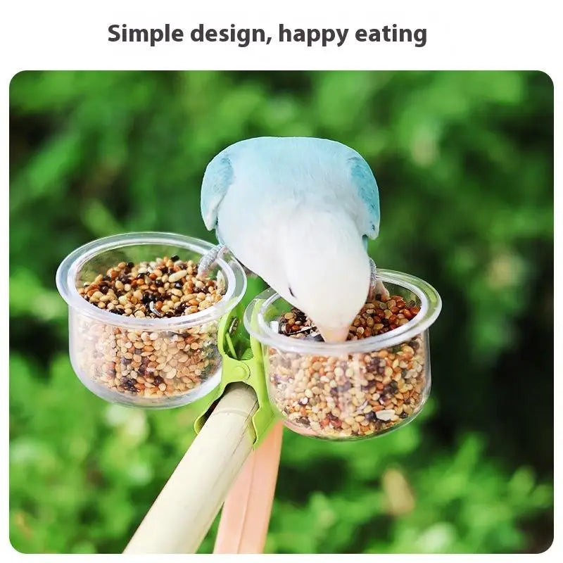 A blue bird is feeding from a clear cup attached to a clip-on feeder with a mounting bracket.