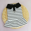 A black and white striped pet dress for a small dog displayed on a woven natural fiber mat.