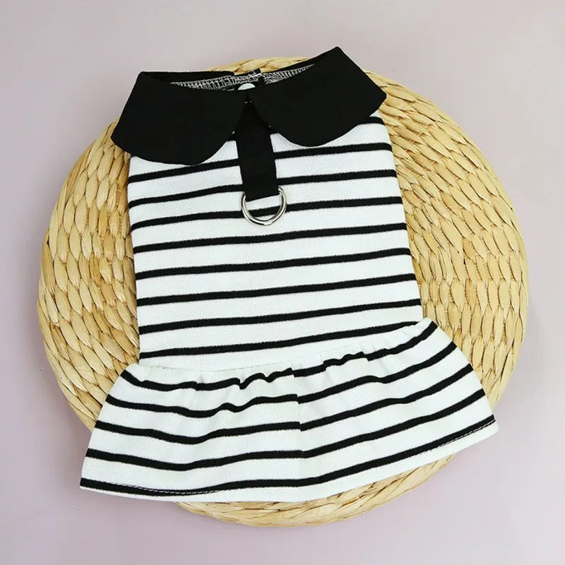 A black and white striped pet dress for a small dog displayed on a woven natural fiber mat.
