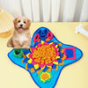 A golden retriever puppy sits next to a blue snuffle mat filled with colorful fabric toys for slow feeding.