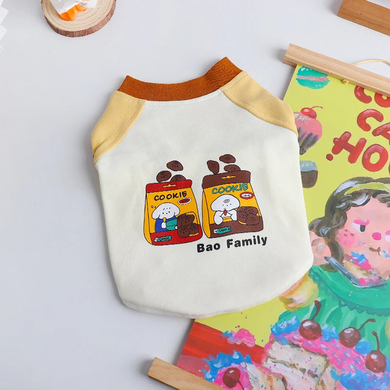 A cream-colored pet vest shirt with a yellow collar and a graphic of a Bao family cooking.