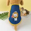 A brown dog wearing a blue mesh vest with a yellow trim featuring a white cat and a lion face print.
