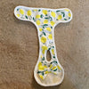 White reusable dog diaper pants with a yellow lemon leaf pattern and a yellow bow detail