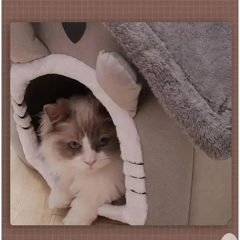 A fluffy gray and white cat is peeking out of a white pet house bed.