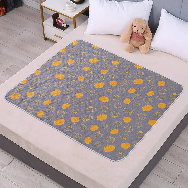A gray patterned waterproof cartoon bed protector pad is placed on a light-colored bed.