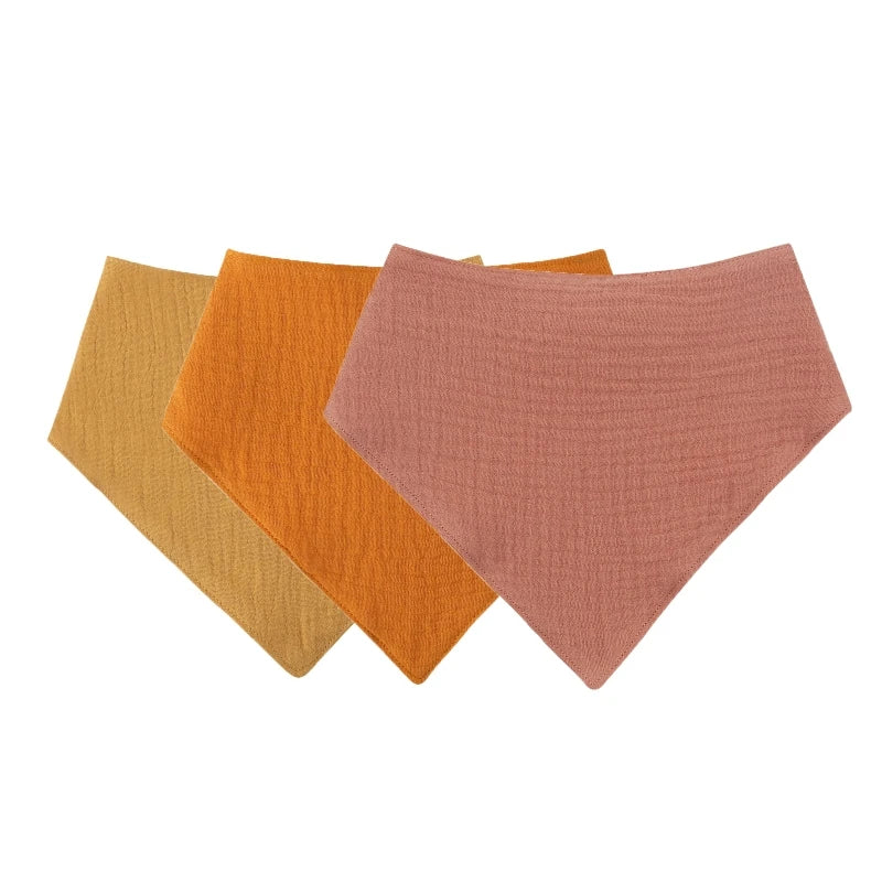 A pack of three soft cotton baby bibs in shades of mustard yellow, orange, and dusty rose.