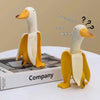 A yellow and white resin banana duck garden sculpture is displayed on a box with text asking what someone should do or who so
