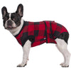A black and white dog wearing a red and black plaid recovery suit.