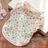 A pink floral princess pet dress for dogs and cats with ruffled trim lying on a wooden surface.