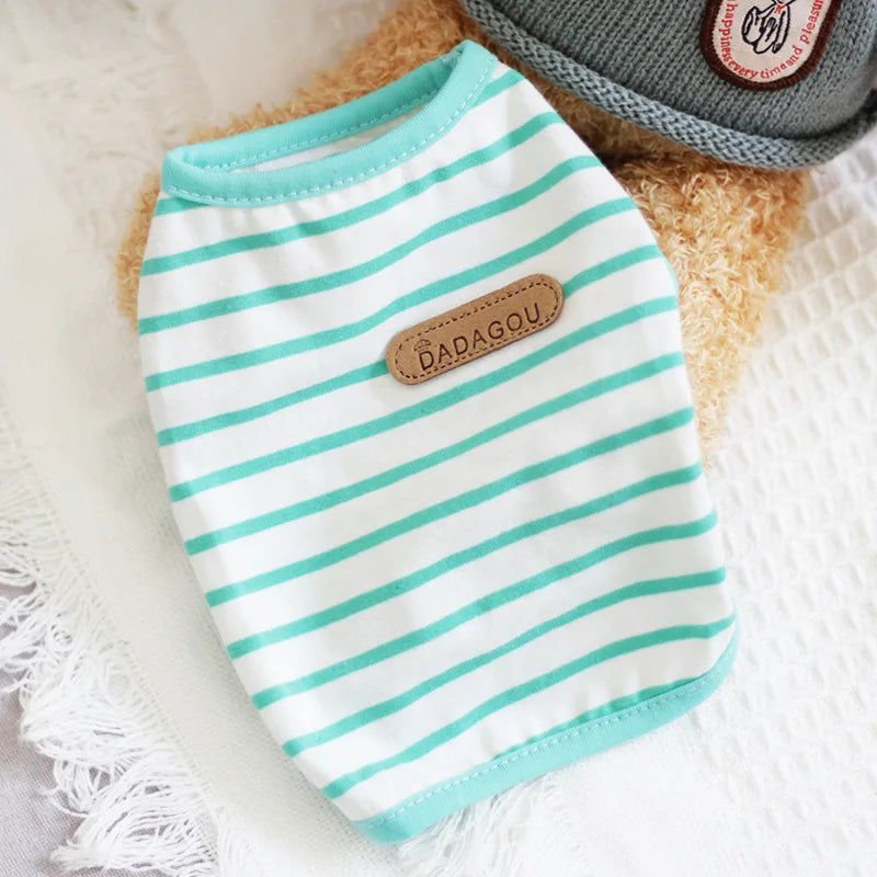 A white and teal striped sleeveless pet vest for small dogs or cats resting on a white textured surface.
