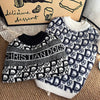 A black and white patterned knit sweater for dogs displayed next to a box.