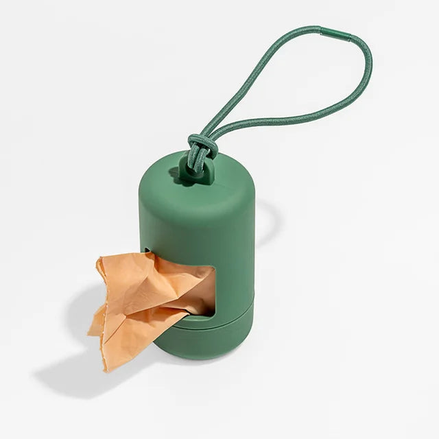 A green portable dog poop bag dispenser with a loop for attaching a bag, shown against a white background.