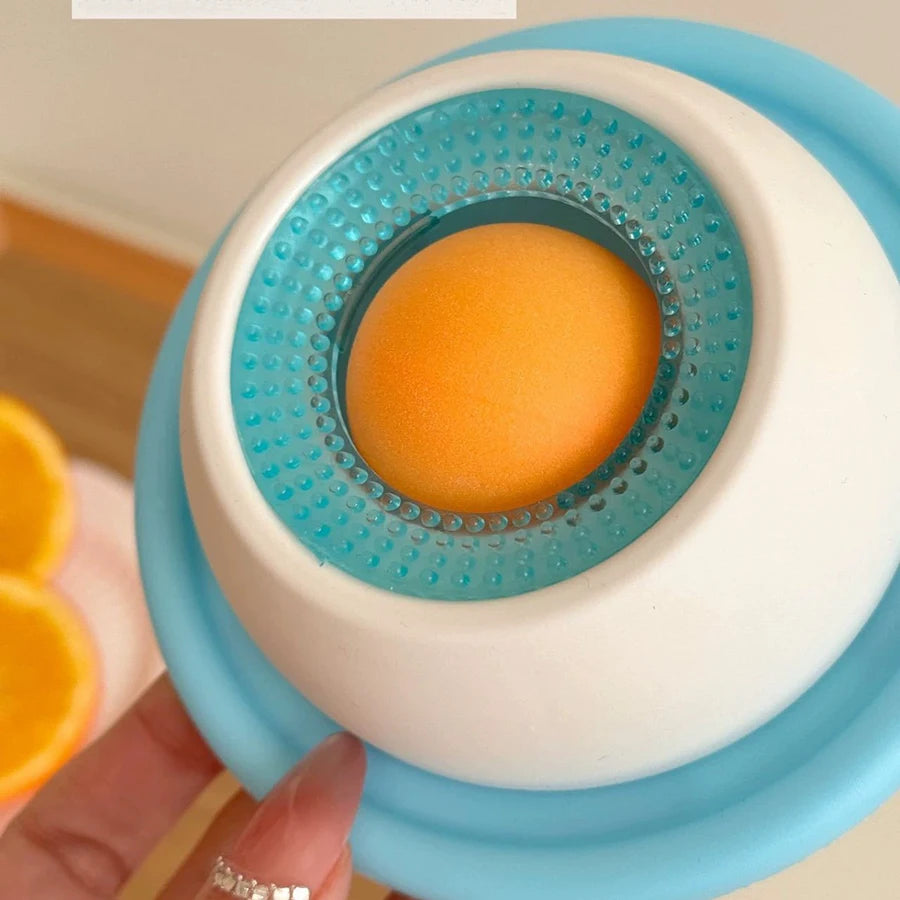 Nahaufnahme eines interaktiven Tier-Lickspielzeugs mit einer orangen Kugel in einer weißen und blauen Silikonschale.