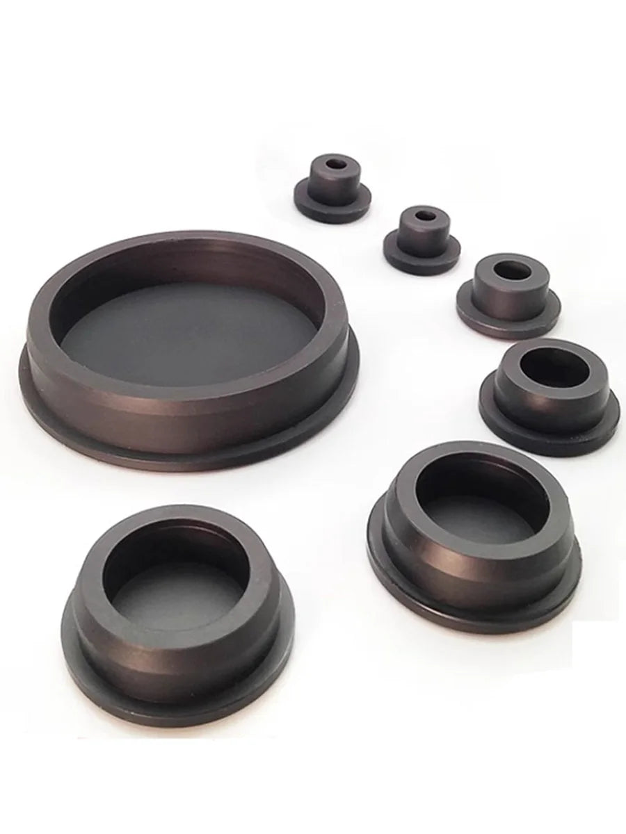 A set of dark gray silicone rubber hole plugs and caps of various sizes arranged on a white background.
