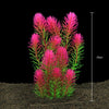 Un amas de plantes aquatiques artificielles roses et vertes poussant dans un substrat sombre.