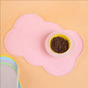 A pink silicone pet feeding mat with a small bowl of dark kibble placed on it.