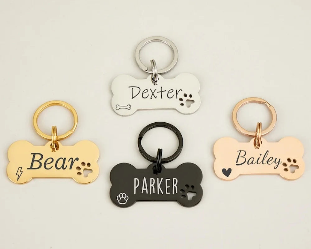 Three custom engraved bone-shaped stainless steel dog ID tags with different names and designs