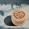 A round wooden keepsake box with a heart engraved on the lid, featuring paw prints and the text You left paw prints on my Hea