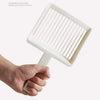 A hand is holding an extra-large white cat litter scoop with a hanging hook.