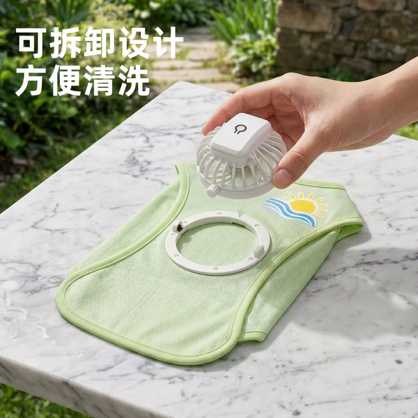 A hand holds a light green cooling dog vest with a built-in fan on a marble surface.